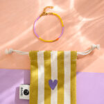 Ava&Yves - Perlenarmband lila/gelb mit Karabinerverschluss und Säckchen in ocker/weiss Ava&Yves - Perlenarmband lila/gelb mit Karabinerverschluss und Säckchen in ocker/weiss